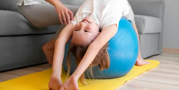 mother-helping-girl-exercise-ball